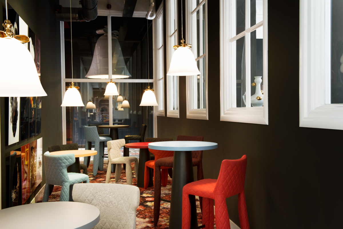 Bell-shaped pendant lighting in dining room with colorful chairs and black walls with windows