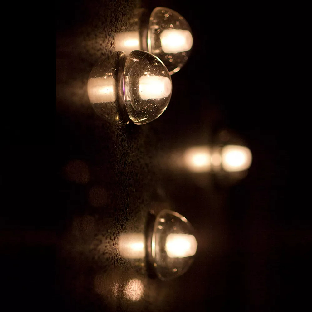 Up close photo of lit globe wall sconces with amber light
