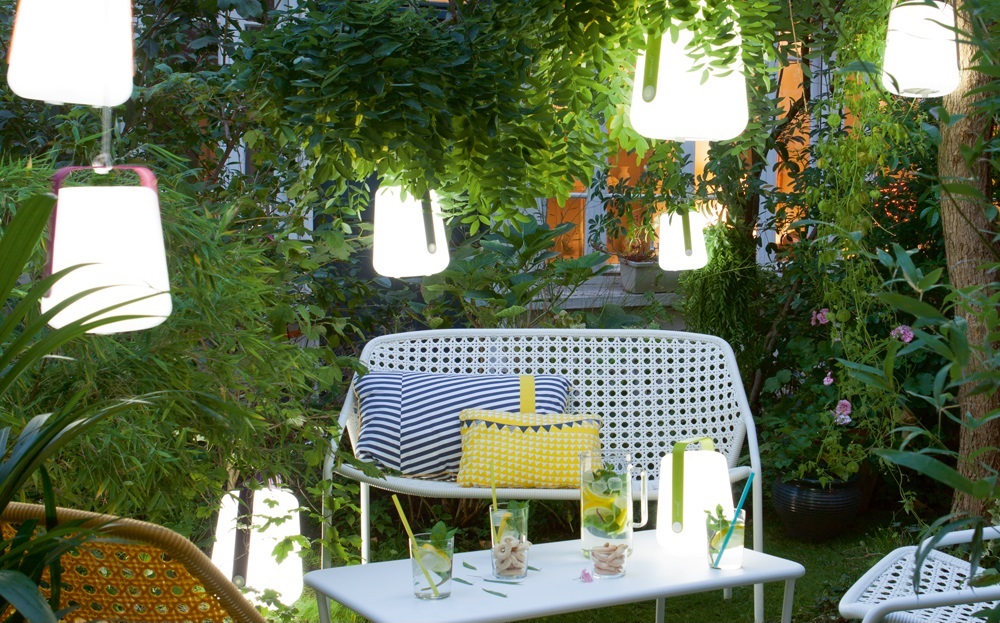 A garden patio illuminated by hanging lights.