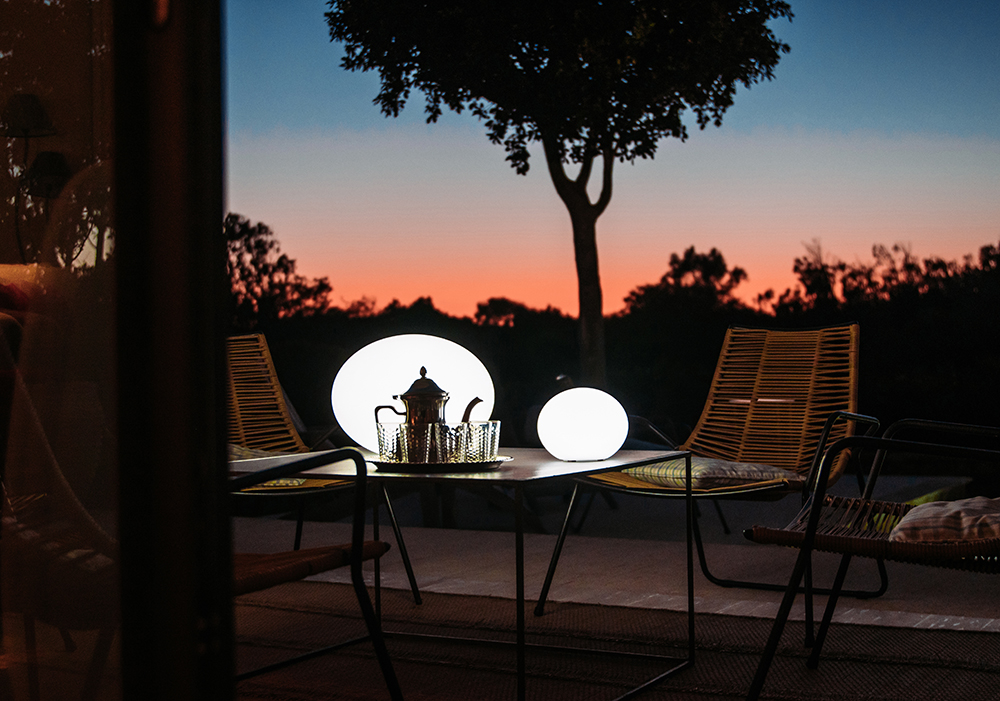 Flatball Bluetooth XXS Floating LED Indoor/Outdoor Lamp on a patio at sunset.