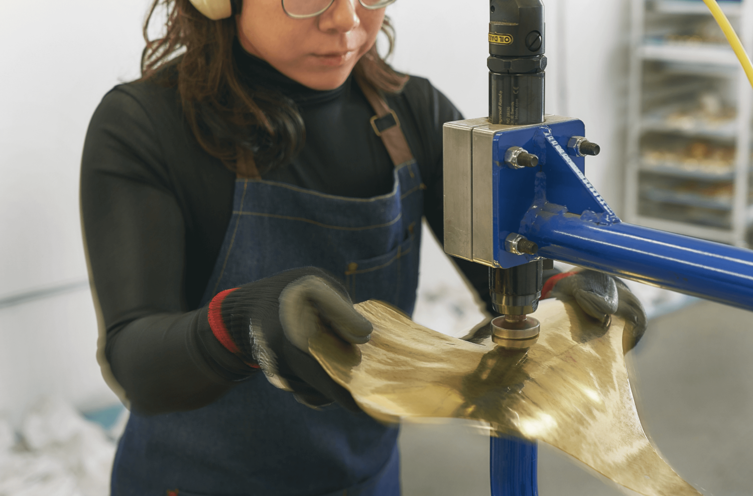 Zoomed in shot of an artist at work with metal in a denim apron