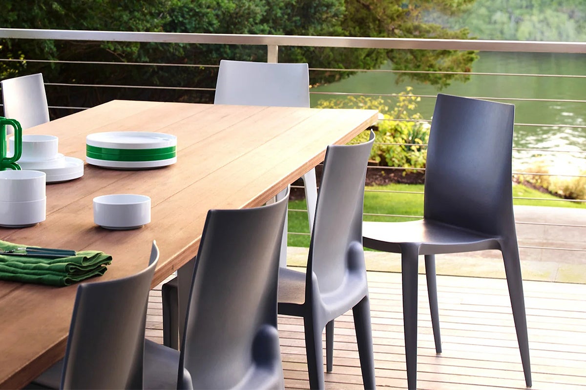 Wooden dining table with grey dining chairs on a deck over open water