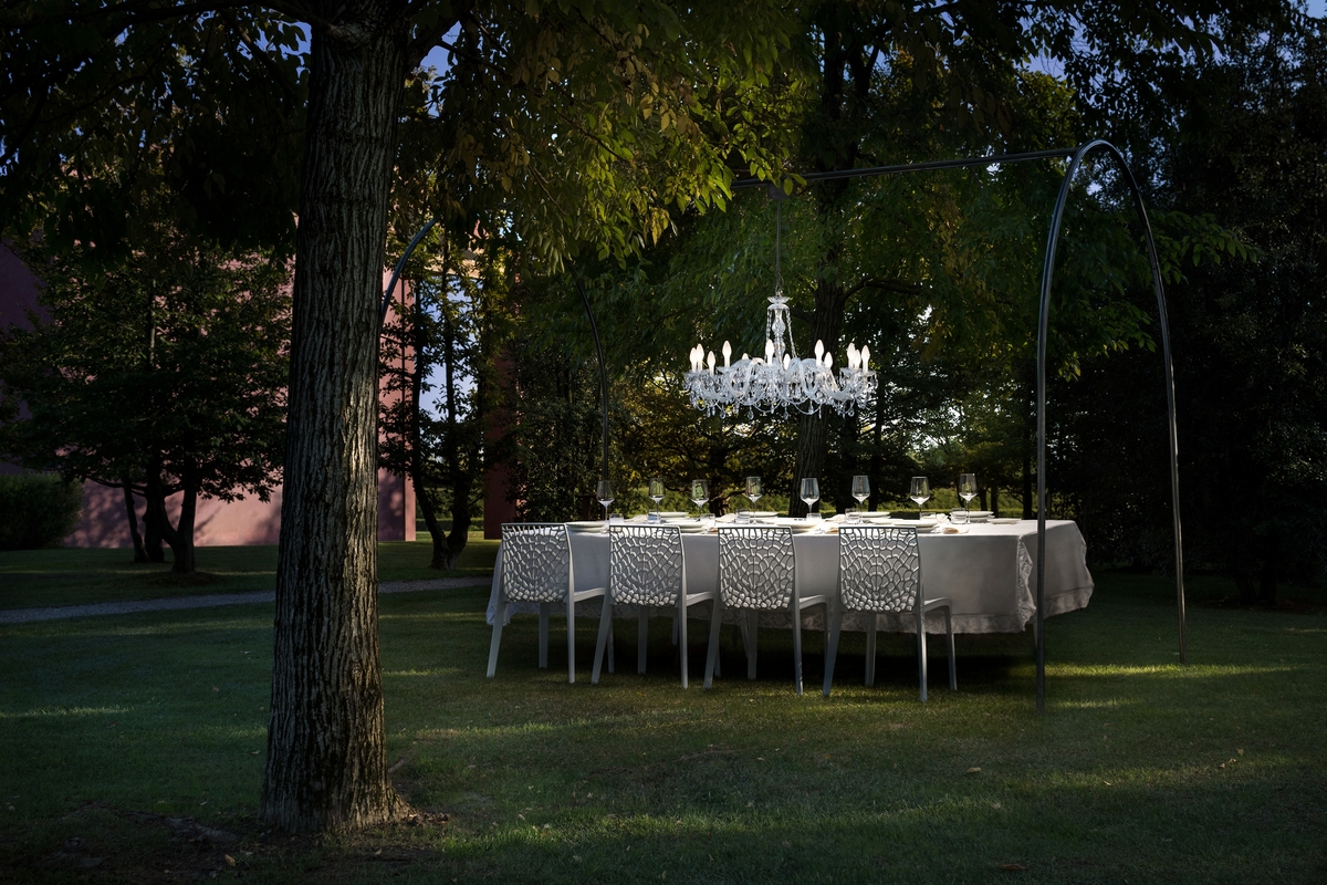 An elegant chandelier above an outdoor dining table.