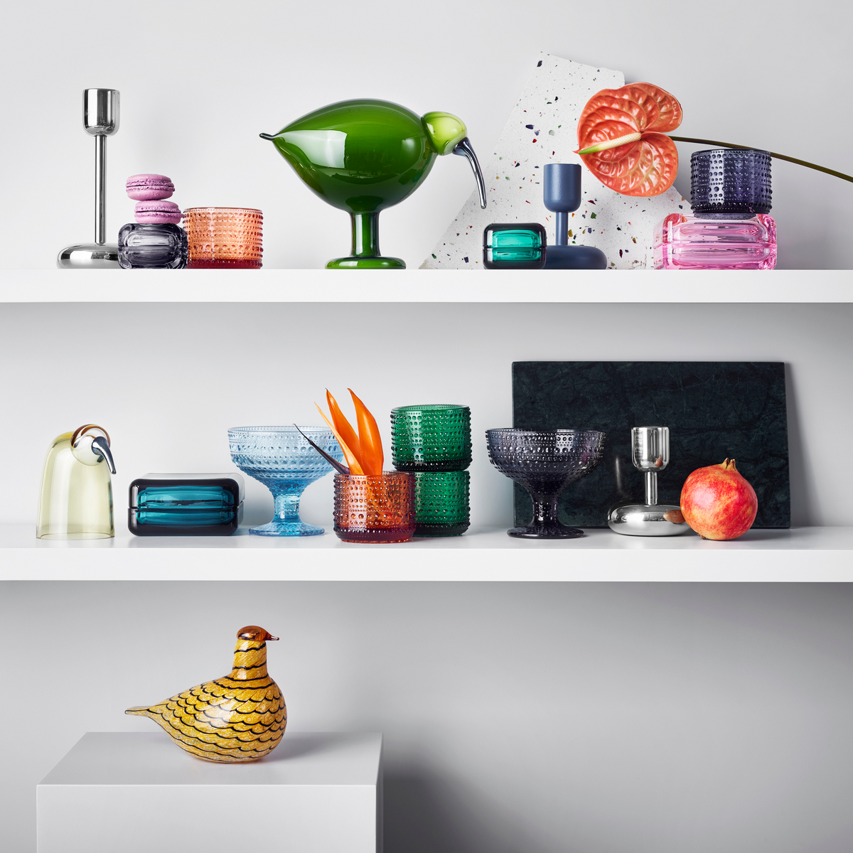 Colorful littala glassware in various shapes on white shelving