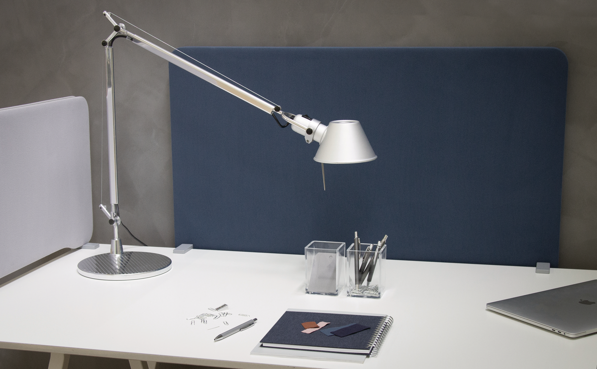 Metallic silver desk lamp on modern white desk with silver Macbook and other silver desk accessories.