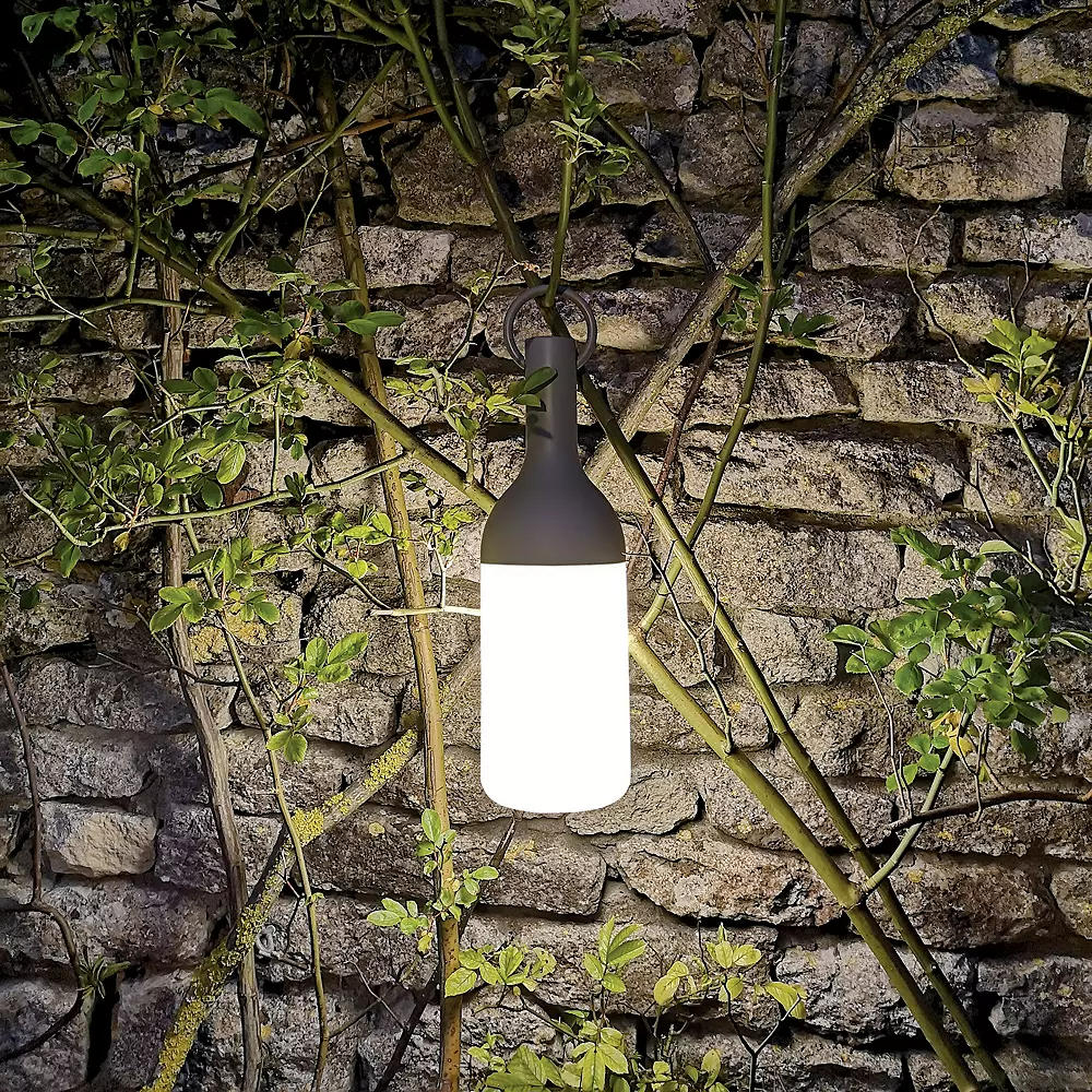 Rechargeable LED Table Lamp hanging in front of a stone wall.