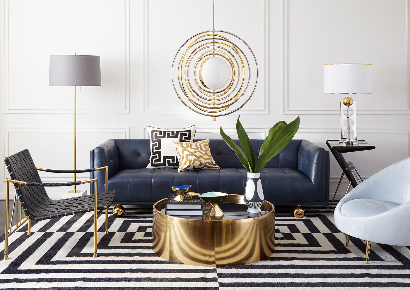 Spherical chandelier over gold coffee table and black and white striped rug in a modern living room