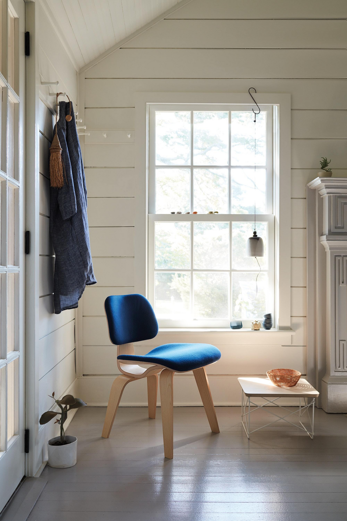 Wooden chair with blue upholstery in a neutral colored corner
