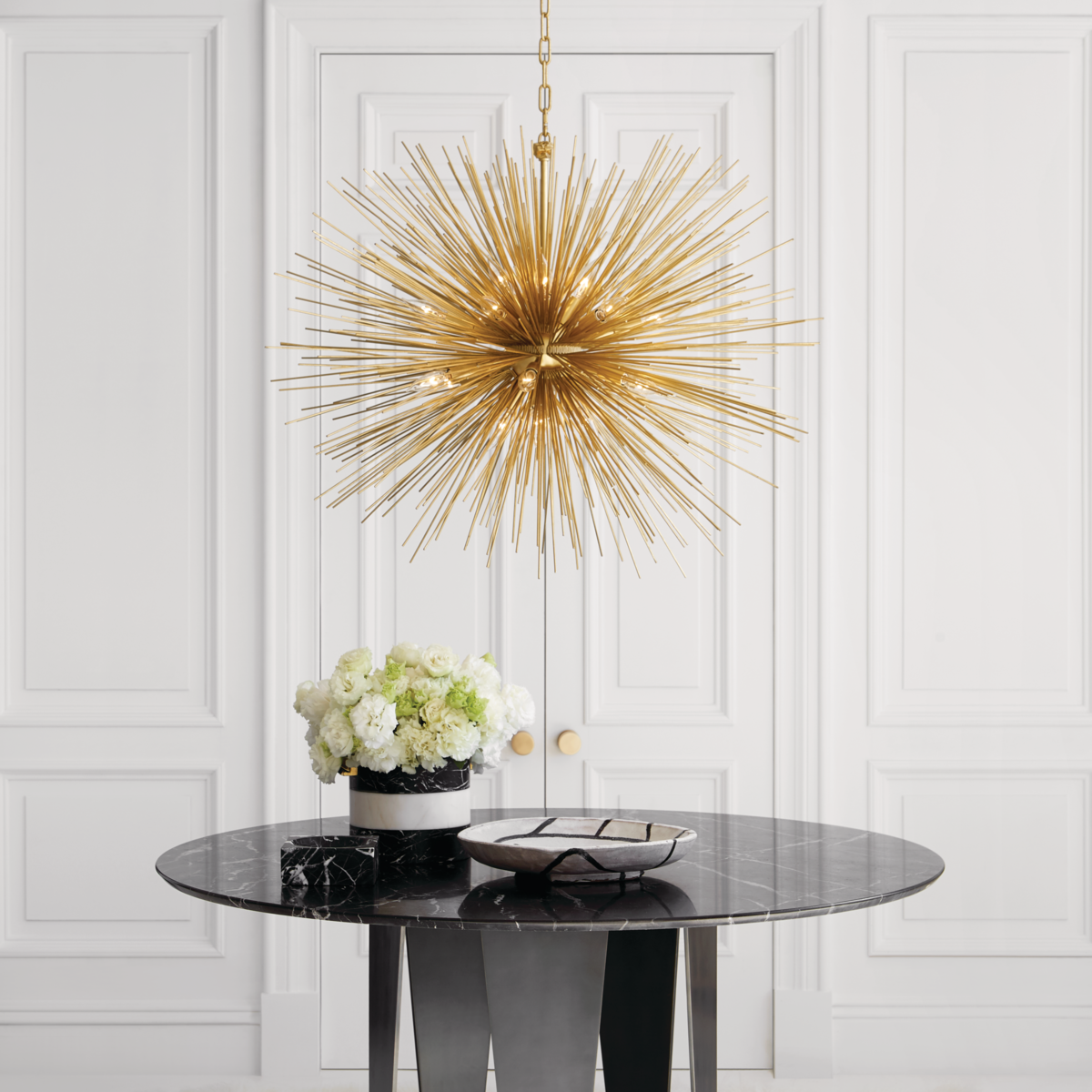 Golden pendant made of spikes over black marble roundtop table with flower centerpiece
