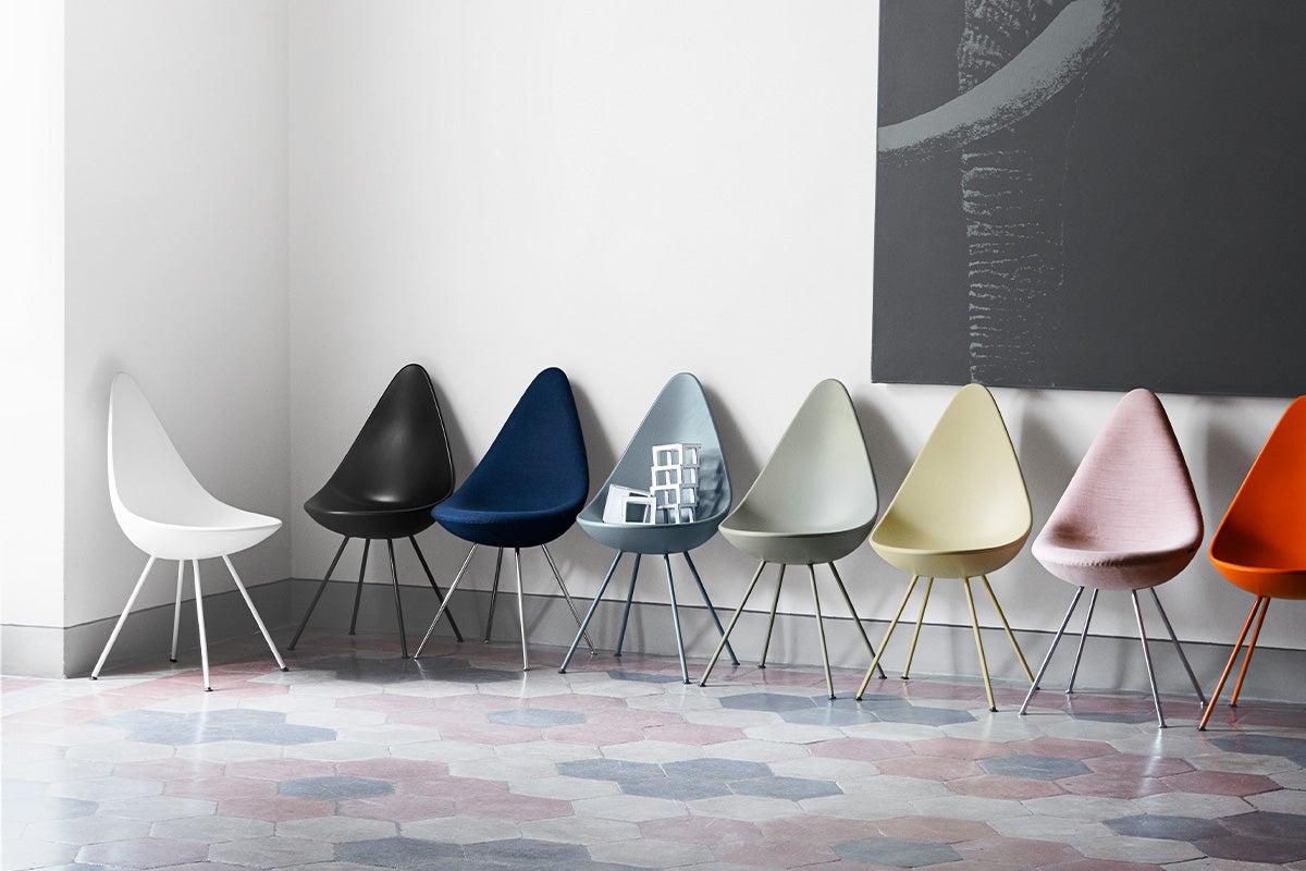 Multi-colored tear drop shaped chairs on a tile floor with white backdrop