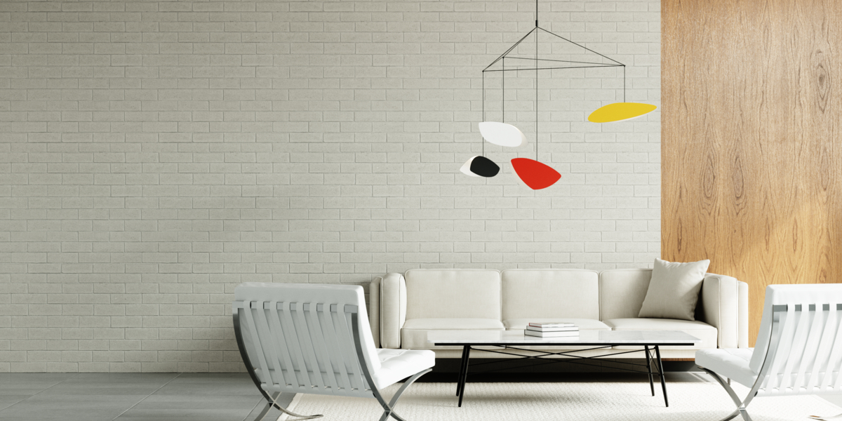 Multi-colored pendant light over mid-century modern style white furniture against white brick wall