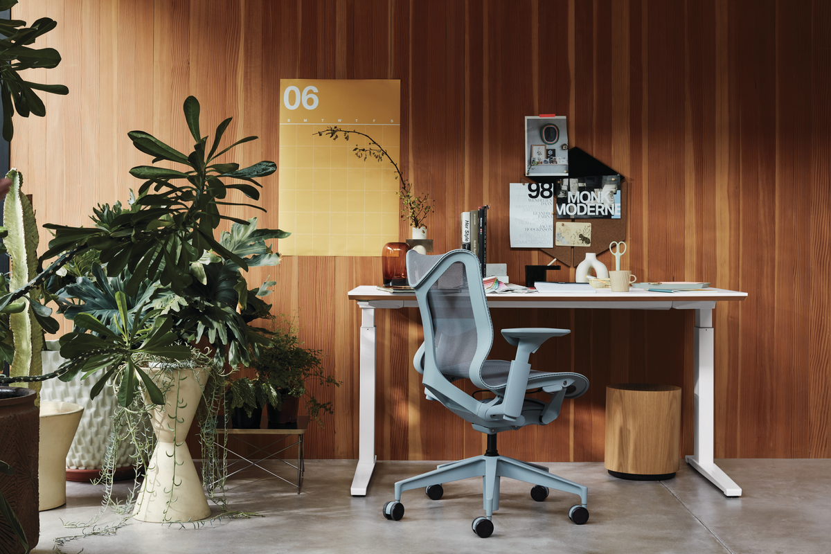 Gray office chair with white desk against wood wall with plant life 