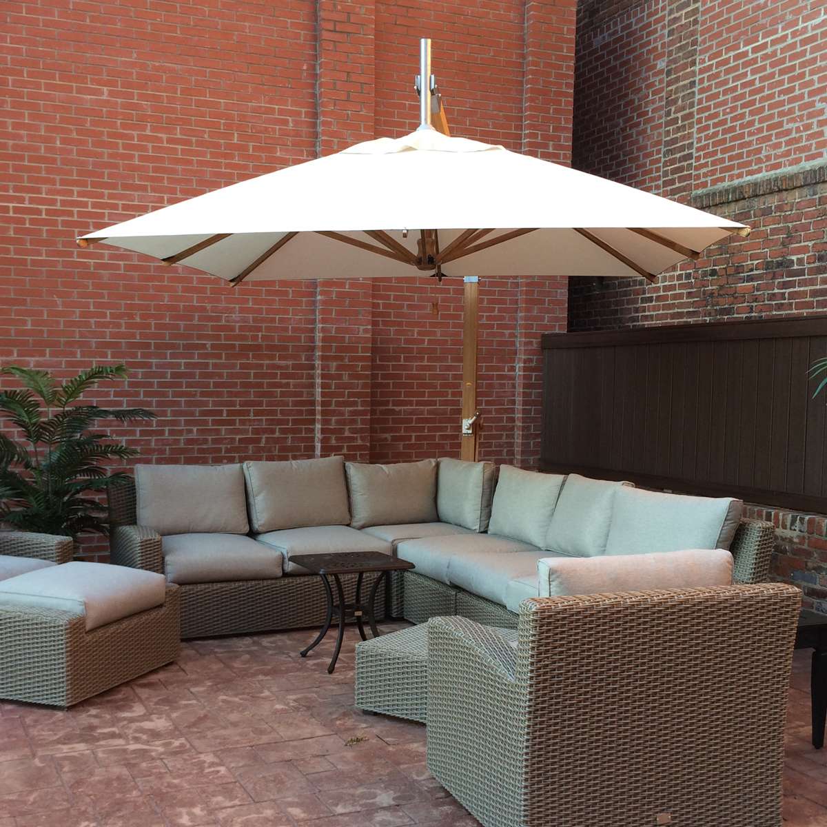 Large outdoor umbrella over lounging furniture against brick wall