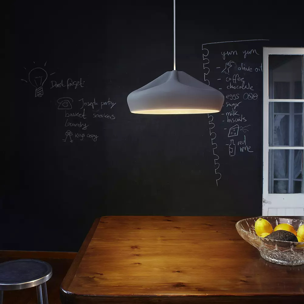 Lit white pendant light over table with black chalkboard background