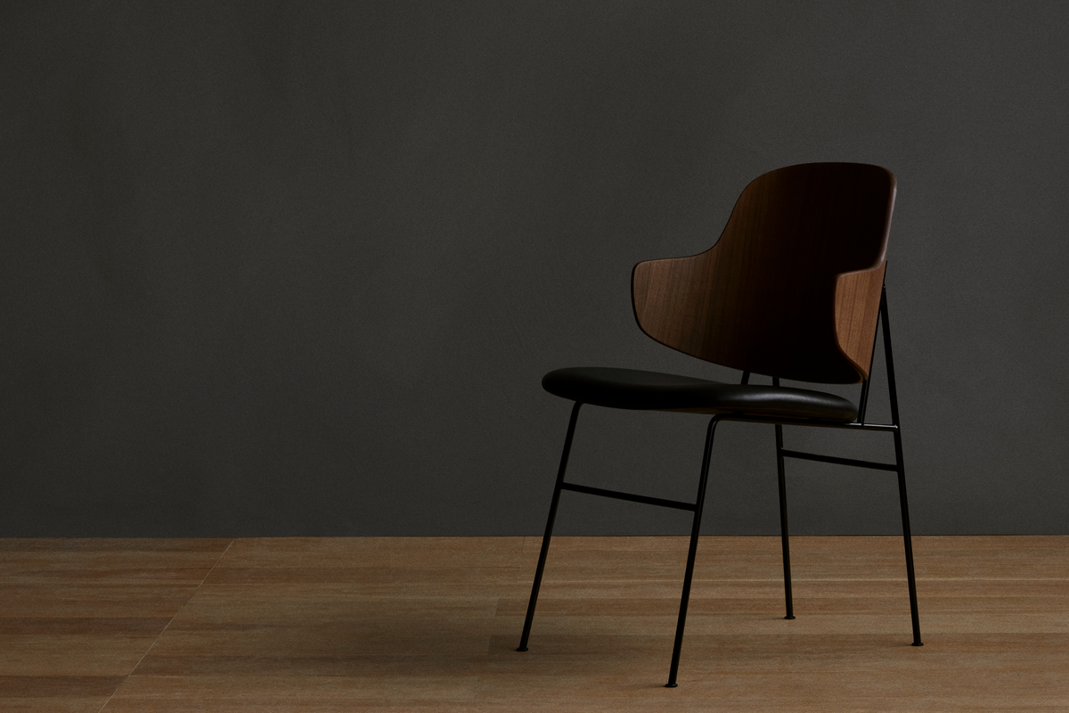 Black and brown chair on hardwood floor with gray backdrop