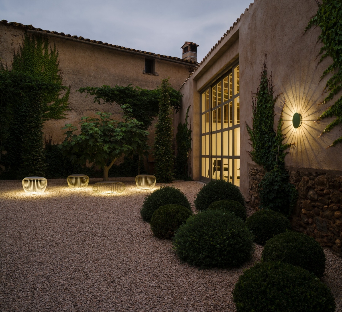 Seating and wall light illuminated in outdoor garden area