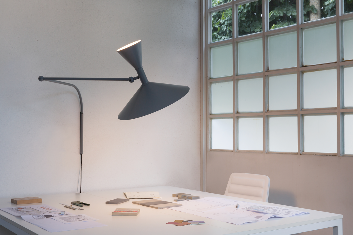 Grey wall sconce over white desk with windows in background