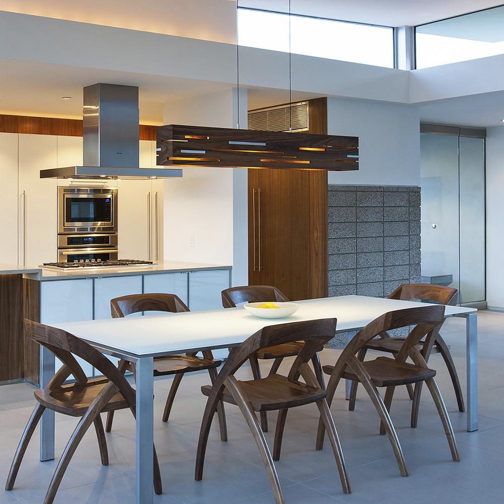 Wood chairs in a dining room complement the wood linear suspension.