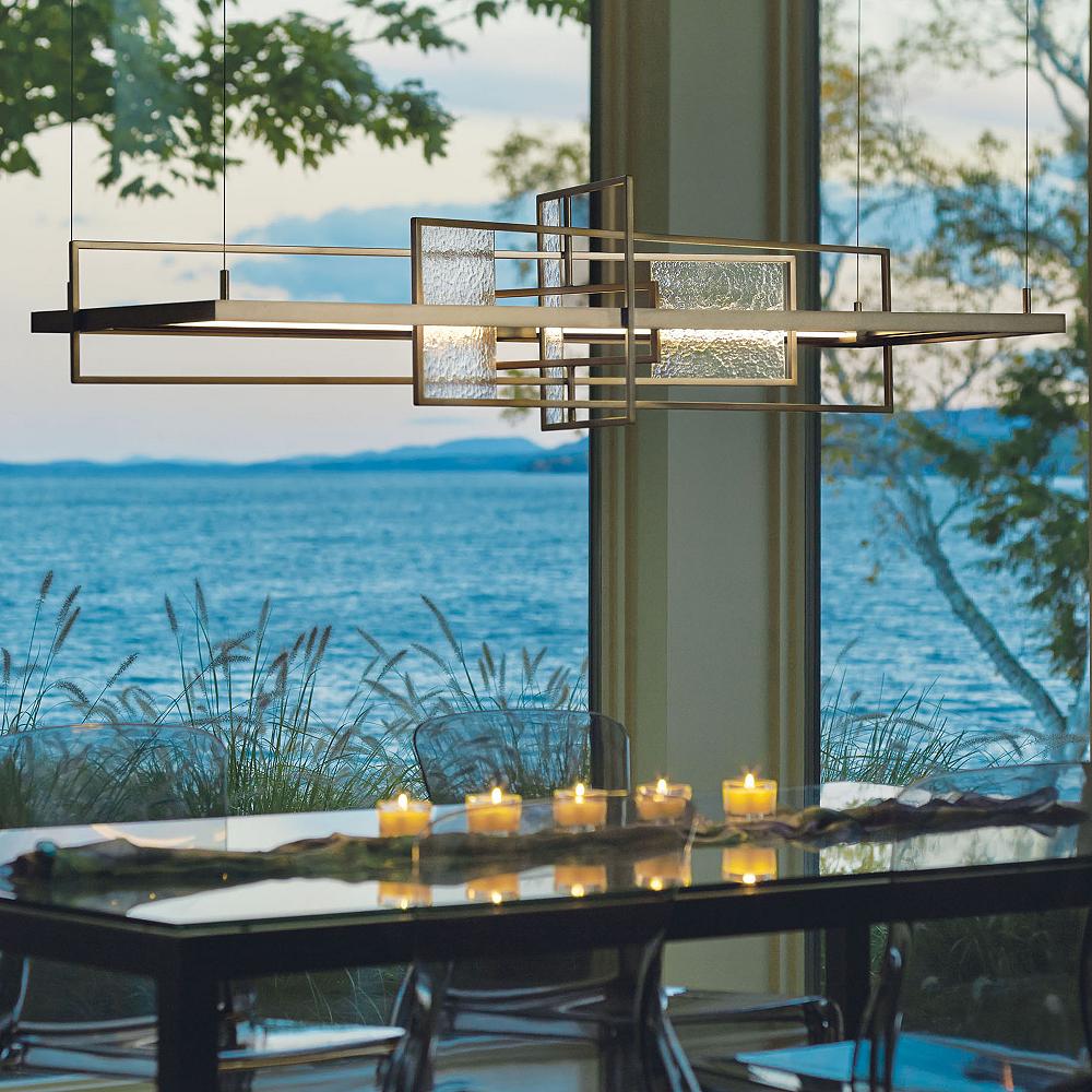 A row of candles accent the light below a lengthy, geometric suspension.