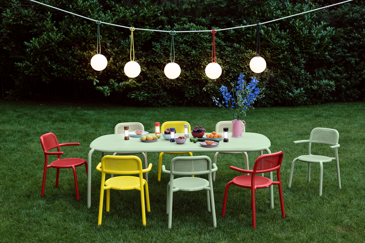 An outdoor dining space lit by hanging pendants on a wire.