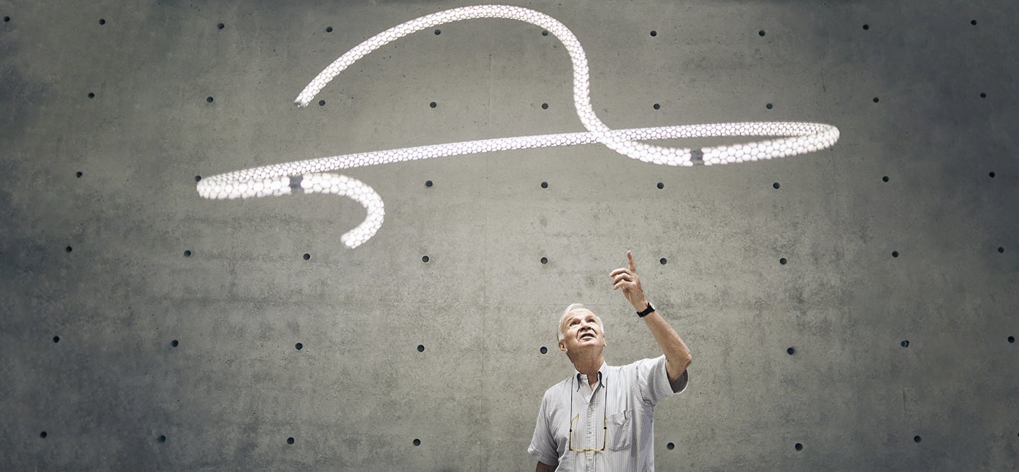 Designer Paolo Rizzatto with his Squiggle LED Chandelier for Rotaliana by LUMINART, only at Lumens.